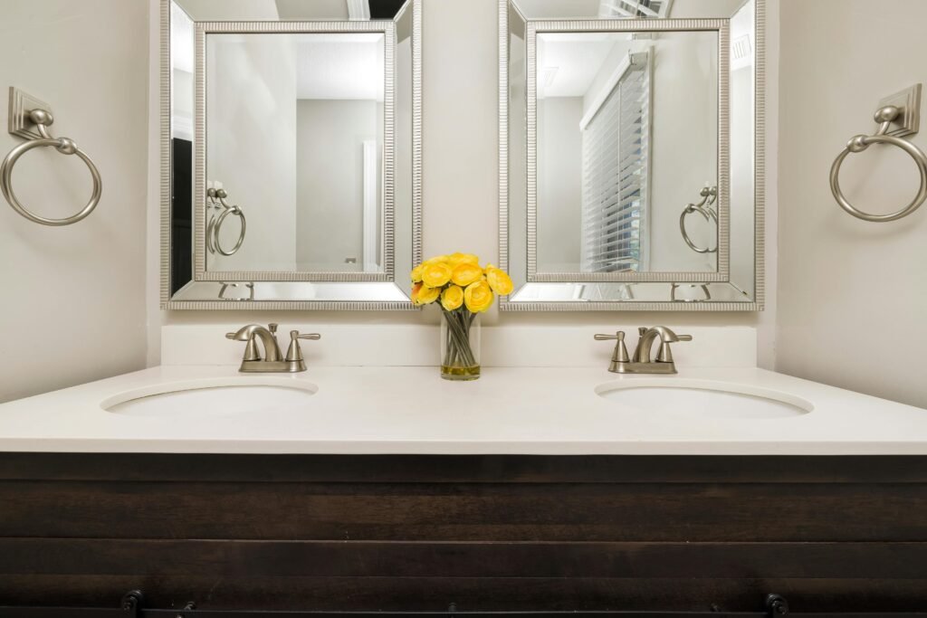 Elegant modern bathroom with twin mirrors, stylish faucets, and a touch of luxury with yellow flowers.