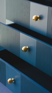 Close-up of a stylish blue dresser with gold knobs, showcasing elegant furniture design.