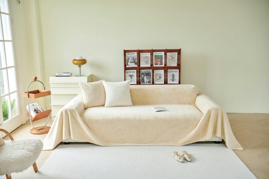 Cream-colored throw on sofa in a bright, modern living room with magazines and decor.